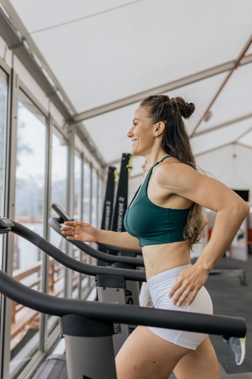 Fit woman jogging on treadmill in an airy gym, focused on health and fitness.